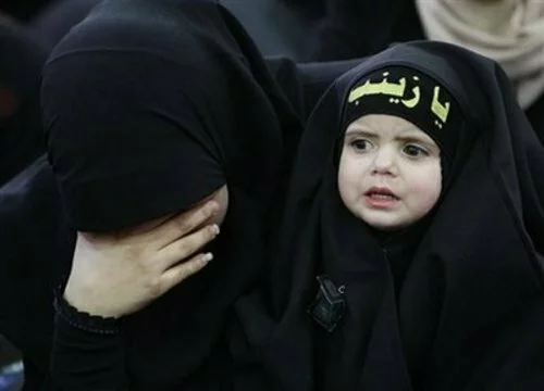 Ashura Muslim woman, holds her daughter wears a head band with Arabic